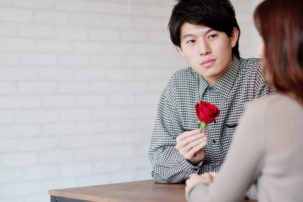 バラの花を持つ男性
